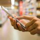Pessoa utilizado smartphone dentro de um supermercado