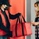Entregador de delivery com uma mochila vermelha entregando o alimento à uma mulher