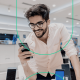 Imagem de um homem sorrido ao olhar a tela do smartphone