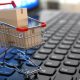 Imagem de uma miniatura de carrinho de supermercado sobre o teclado de um computador