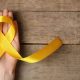 Laço amarelo sobre uma mão feminina