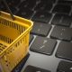 Imagem de um cesto de compras amarelo sobre o teclado de um notebook