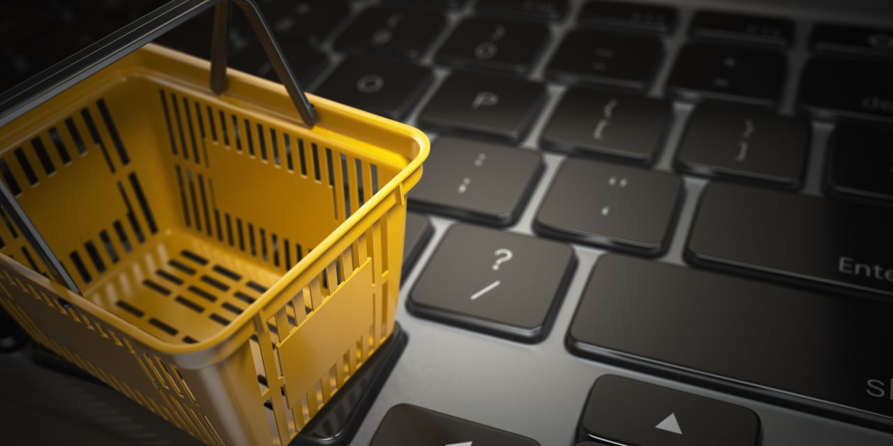 Imagem de um cesto de compras amarelo sobre o teclado de um notebook