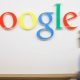 Imagem da palavra Google em uma parede e uma pessoa caminhando próxima a ela