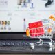 Imagem de uma miniatura de carrinho de supermercado sobre o teclado de um notebook